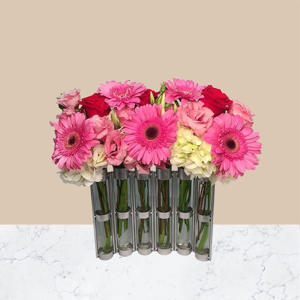 Beautiful, freshly picked spring flowers including roses, lisianthus, roses, gerberas and hydrangea blooms fill this unique snake vase, to create a long, full blooming garden,